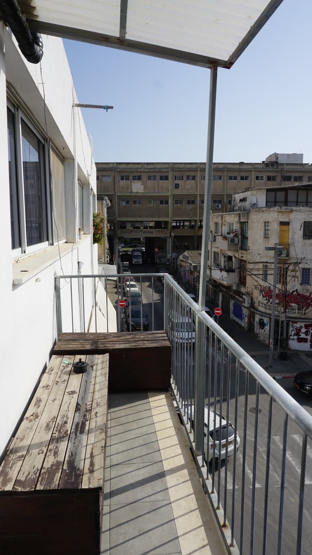 Balcony — metal rail, wood deck, street and skyline below